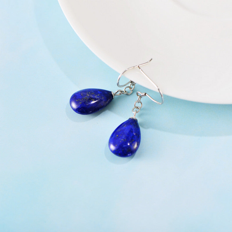 Boucles d'oreilles en lapis lazuli sur fond bleu clair