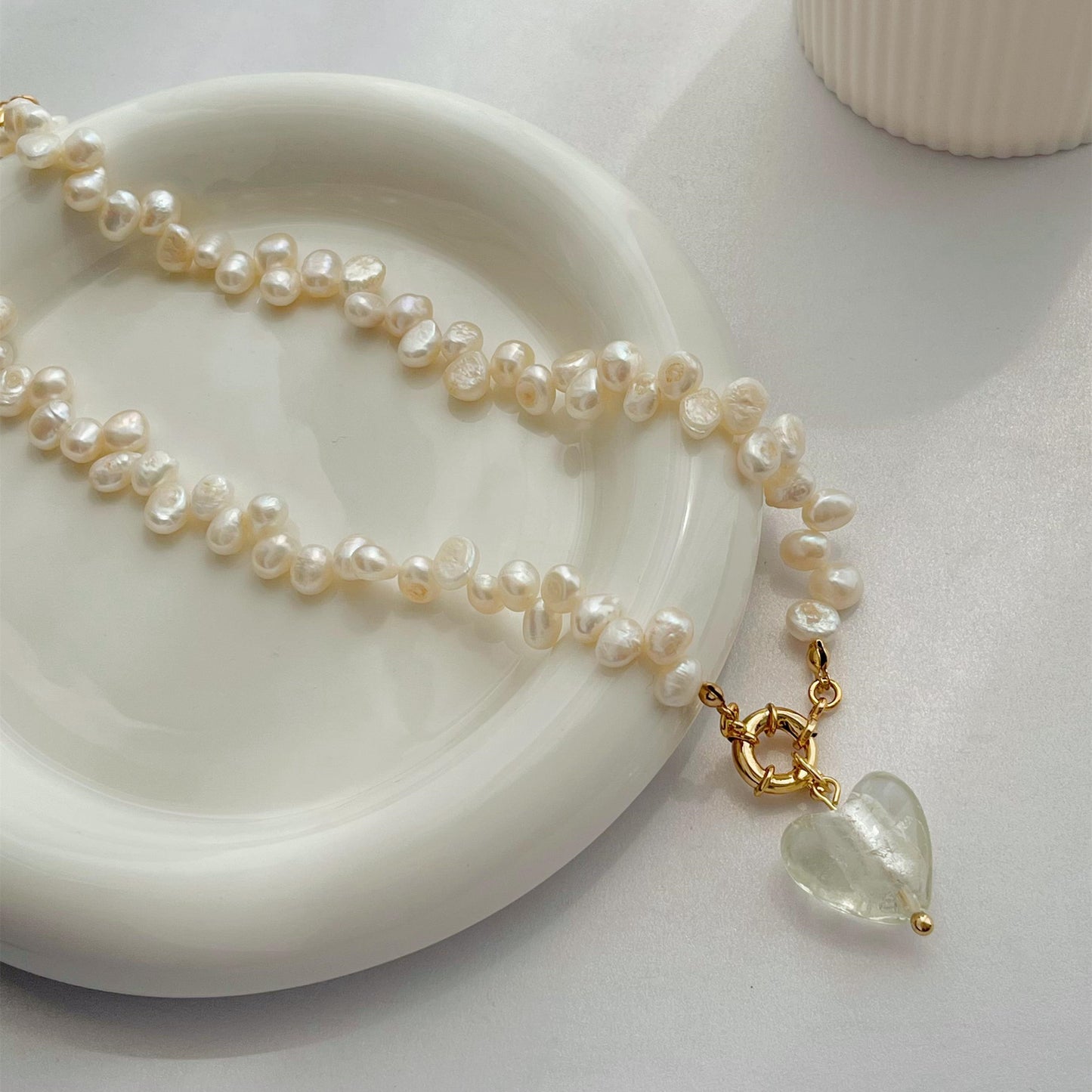 Collier en verre avec perle naturelle sur assiette blanche