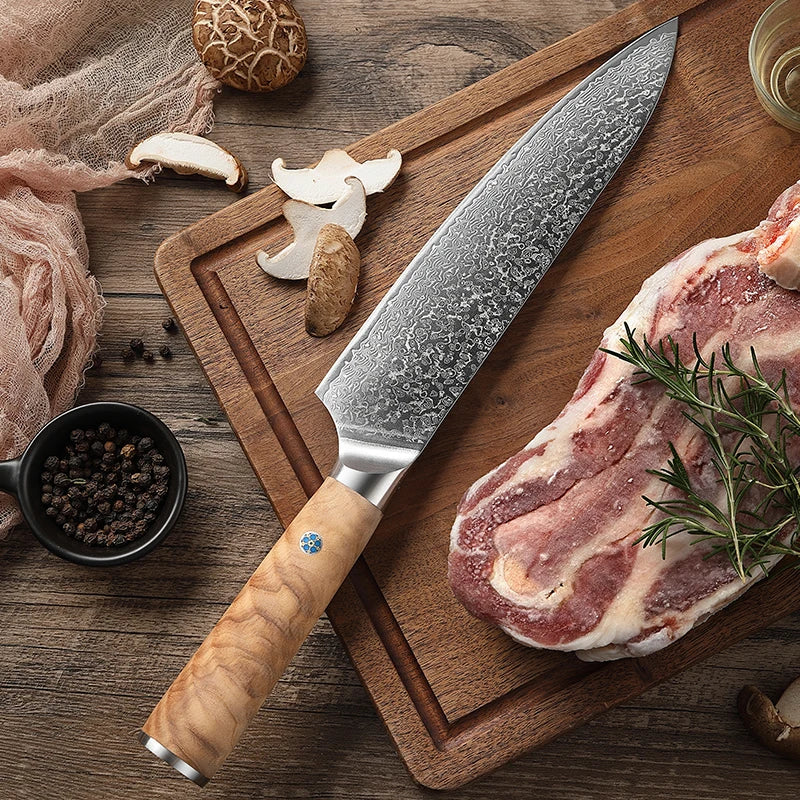 Couteau de chef Gyuto en acier damas avec manche en bois d'olivier, posé sur une planche en bois à côté de tranches de viande et de champignons coupés, illustrant la précision et la polyvalence de ce couteau pour la préparation culinaire.