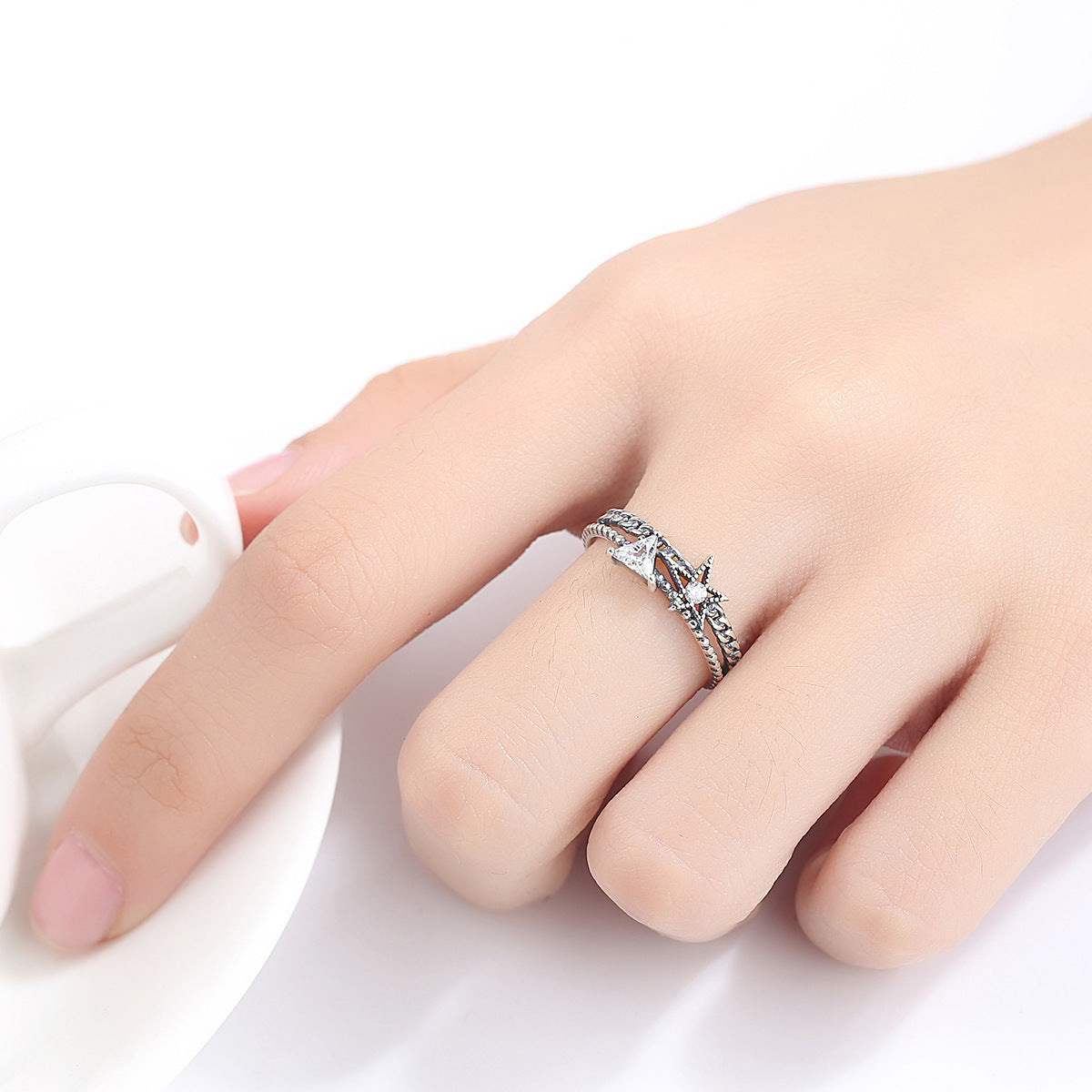 Une main féminine portant élégamment la bague en argent Sterling S925 blanche avec un design en étoile, ajoutant une touche de raffinement et de glamour.