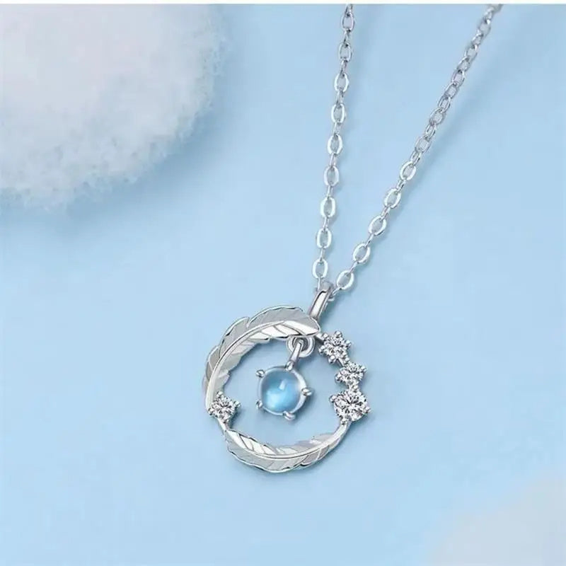 Collier plume argent 925 avec pierre de lune sur fond bleu