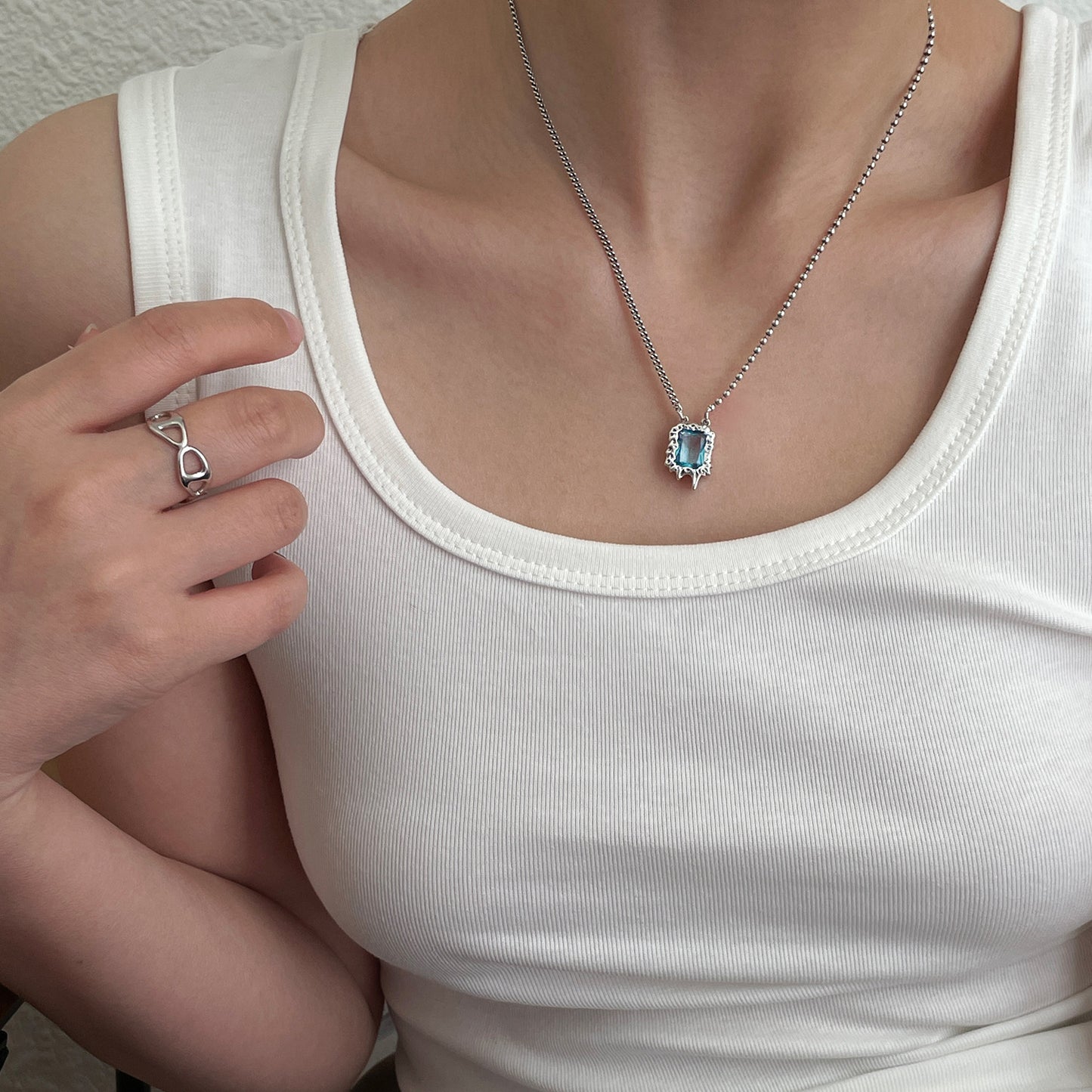 Collier en argent S925 avec zircon bleu sur débardeur blanc.