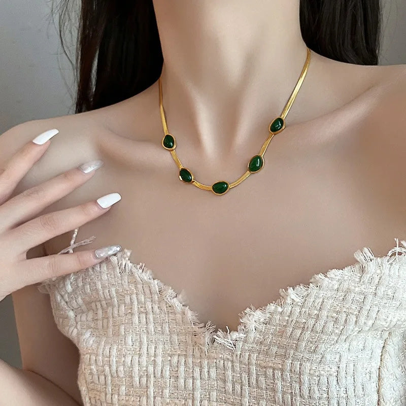 Collier avec pierres vertes sur modèle en robe blanche.