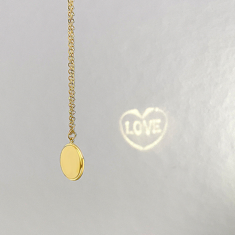 Collier doré avec projection 'LOVE' sur fond gris