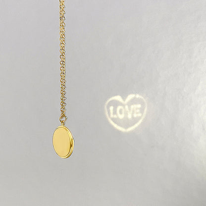 Collier doré avec projection 'LOVE' sur fond gris