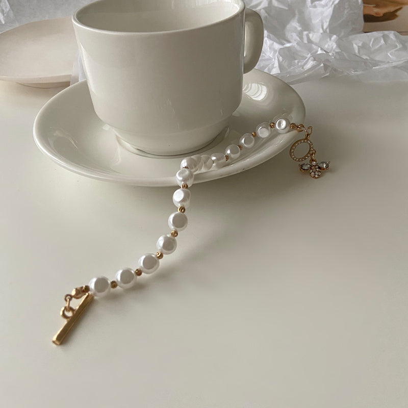 Bracelet perle posé à côté d'une tasse blanche.