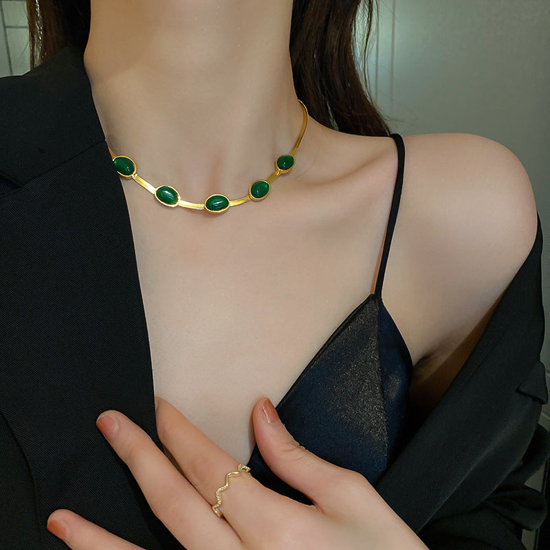 Collier élégant avec pierres vertes sur modèle en noir.