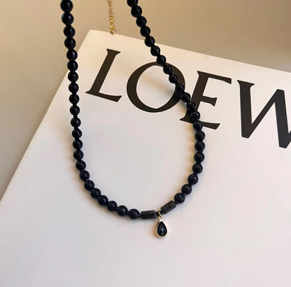 Collier de perles noires avec pendentif sur livre