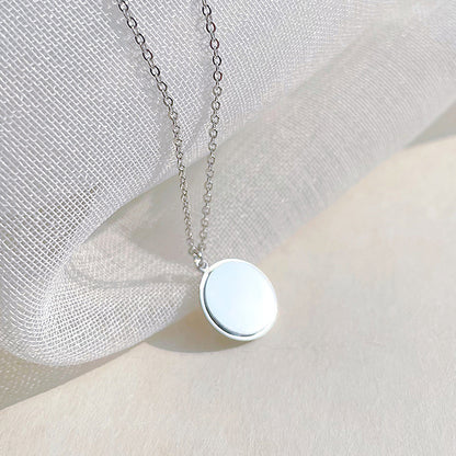 Collier pendentif rond en argent sur tissu blanc