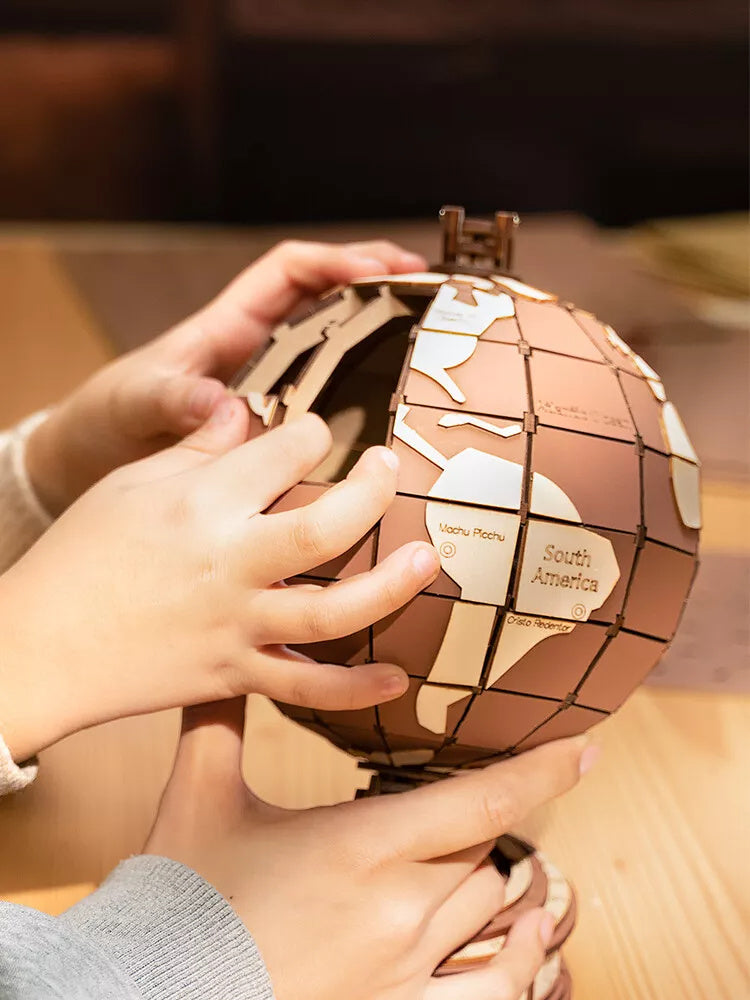 Assemblage du puzzle 3D globe en bois par des mains