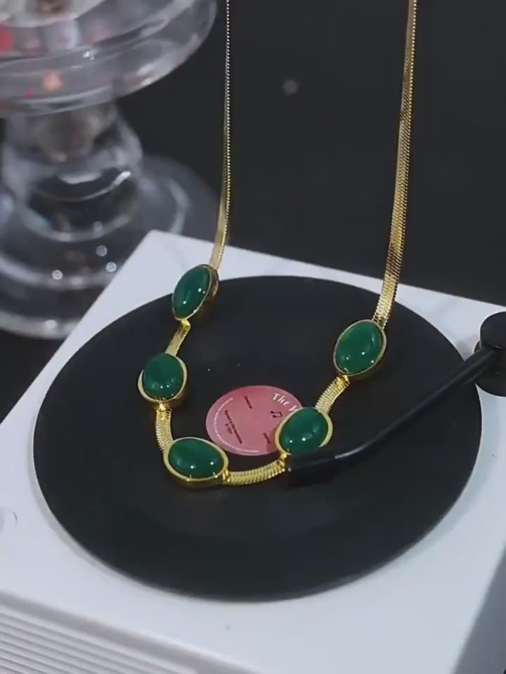 Collier avec pierres vertes sur tourne-disque.