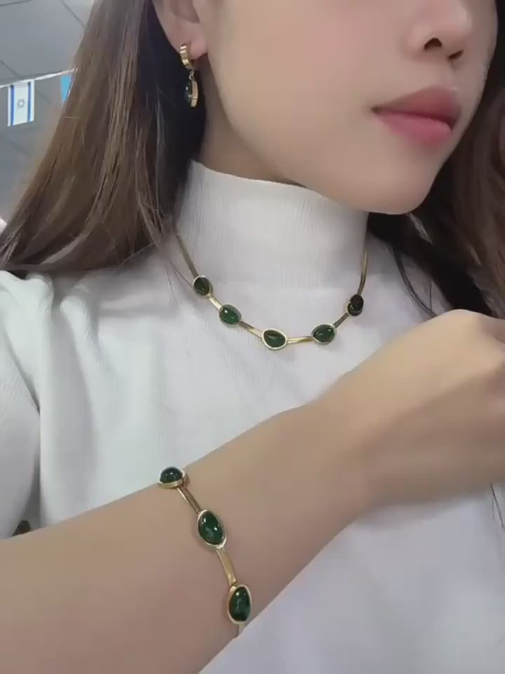 Collier et bracelet avec pierres vertes sur modèle en blanc.